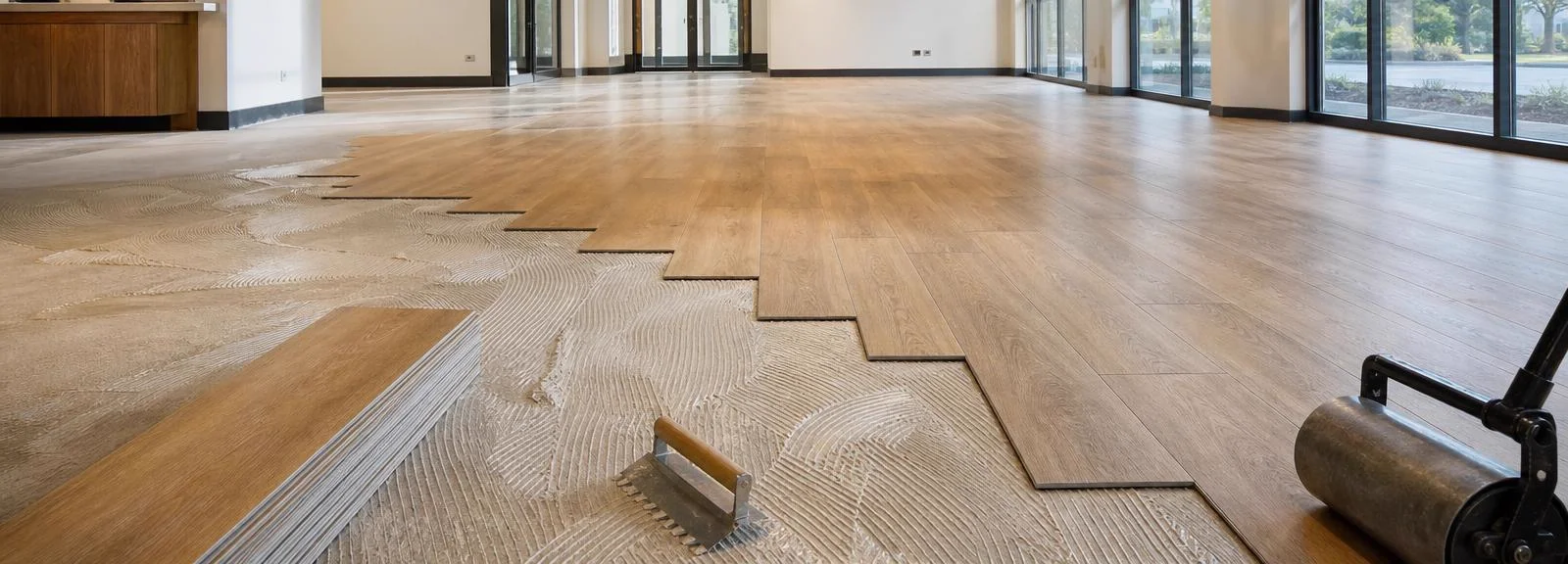 Installer applying glue down luxury vinyl plank flooring